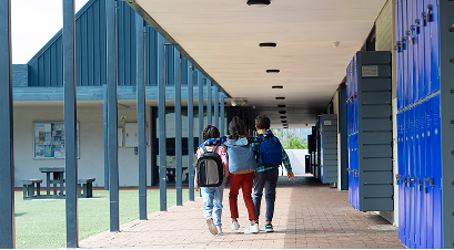 three-children-walk-down-school-corridor-arms-around-each-other-with-copy-space 1